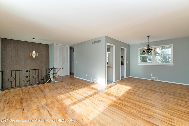 spare room featuring hardwood / wood-style flooring and a chandelier