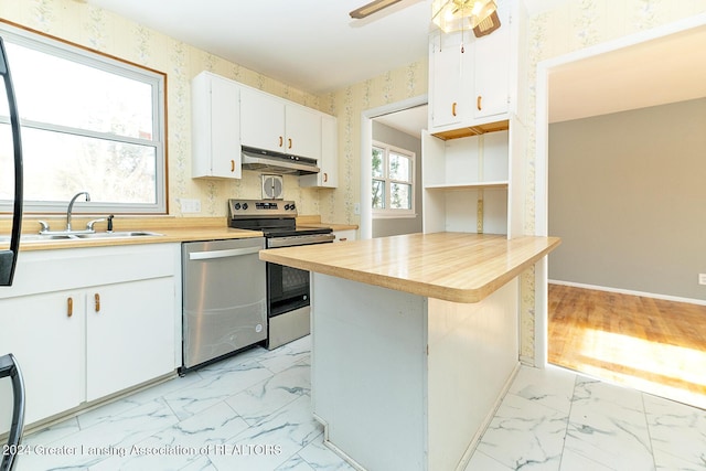 kitchen with kitchen peninsula, a breakfast bar, stainless steel appliances, sink, and white cabinetry