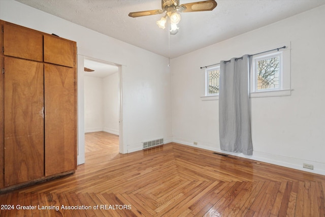 unfurnished bedroom featuring ceiling fan, light parquet flooring, and a textured ceiling