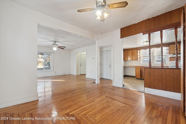 unfurnished living room featuring ceiling fan, a textured ceiling, and light parquet floors