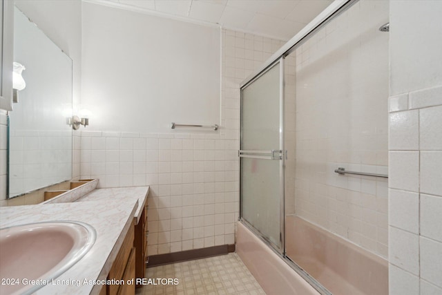 bathroom with vanity, enclosed tub / shower combo, and tile walls