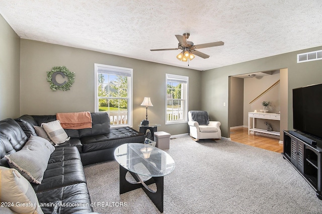 living room with light carpet, a textured ceiling, and ceiling fan