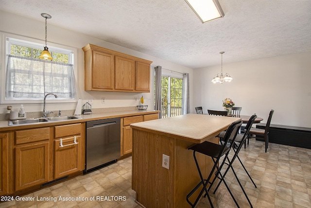 kitchen with stainless steel dishwasher, sink, pendant lighting, an inviting chandelier, and a center island