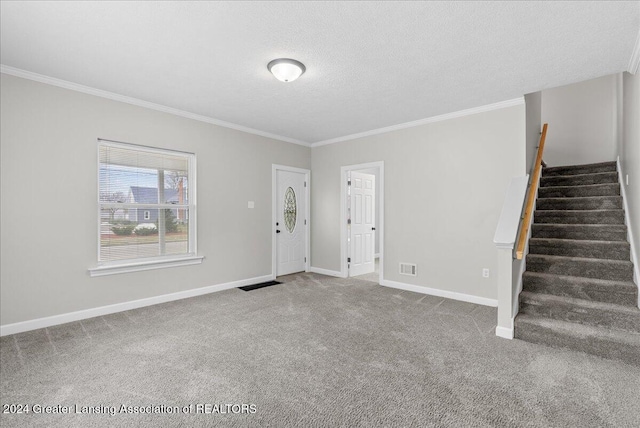 foyer entrance featuring carpet flooring, ornamental molding, and a textured ceiling