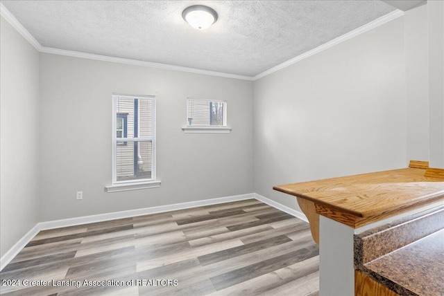 empty room with hardwood / wood-style floors, a textured ceiling, and crown molding