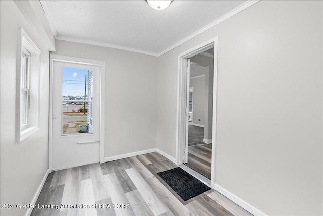 doorway with a textured ceiling, light hardwood / wood-style flooring, and ornamental molding