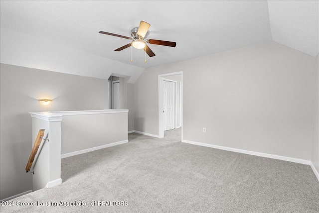 additional living space featuring ceiling fan, light colored carpet, lofted ceiling, and a textured ceiling