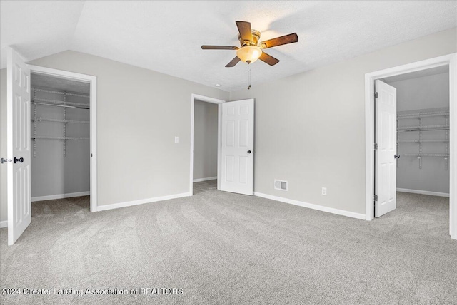 unfurnished bedroom featuring a textured ceiling, light colored carpet, ceiling fan, and lofted ceiling