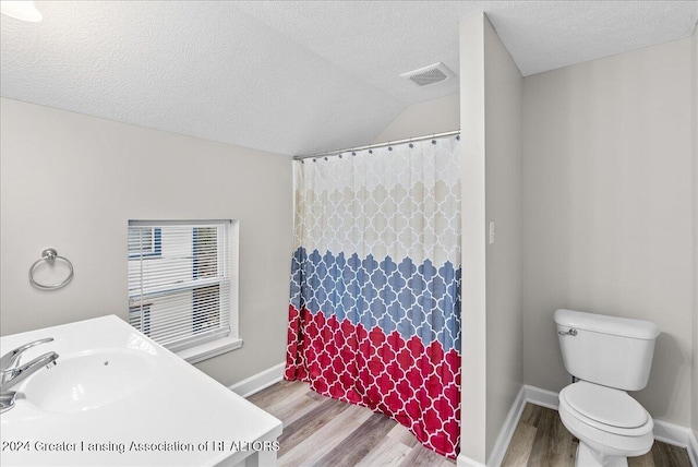 bathroom with hardwood / wood-style floors, toilet, lofted ceiling, and a textured ceiling