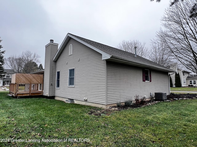 view of side of home with central AC unit, a wooden deck, and a yard