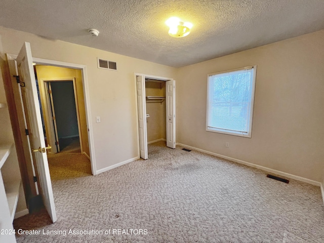 unfurnished bedroom with light colored carpet, a closet, and a textured ceiling