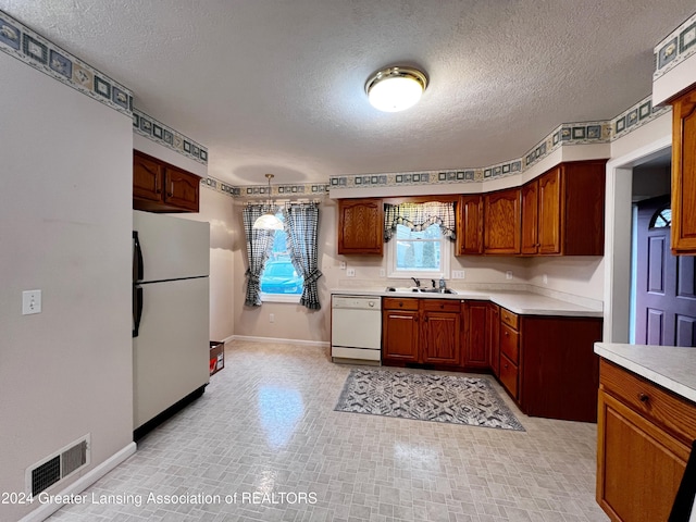 kitchen with dishwasher, refrigerator, hanging light fixtures, and a textured ceiling