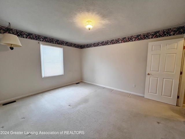 carpeted empty room with a textured ceiling