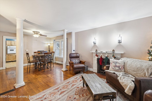 living room featuring wood-type flooring, ceiling fan, and a tiled fireplace