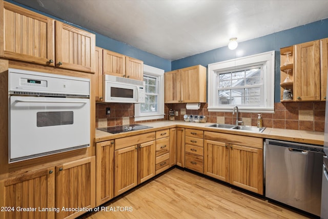 kitchen featuring white appliances, backsplash, sink, light hardwood / wood-style flooring, and tile counters