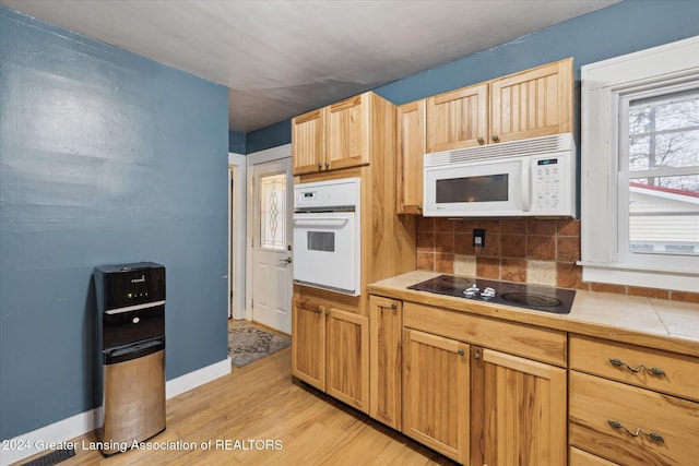 kitchen with light brown cabinets, tasteful backsplash, tile countertops, light hardwood / wood-style floors, and white appliances