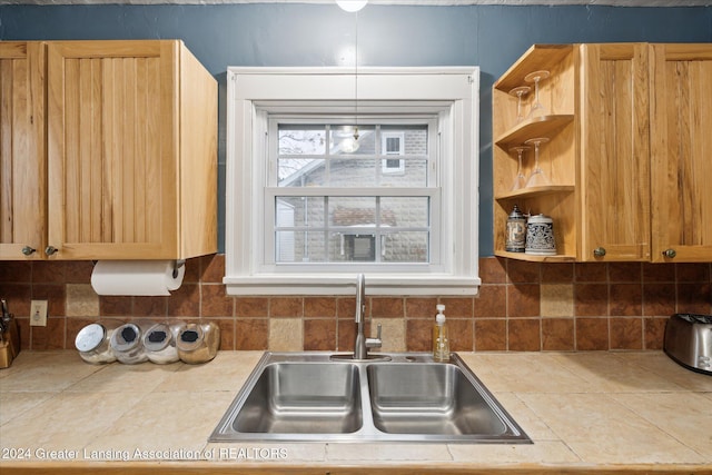 kitchen with backsplash, tile counters, and sink