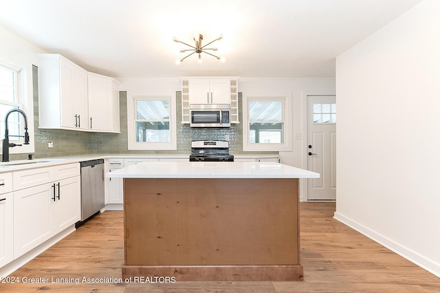 kitchen featuring stainless steel appliances, a kitchen island, a wealth of natural light, and sink