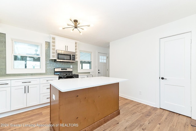 kitchen featuring appliances with stainless steel finishes, tasteful backsplash, a center island, light hardwood / wood-style floors, and white cabinetry