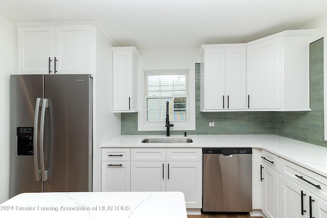 kitchen featuring sink, light stone countertops, tasteful backsplash, white cabinetry, and stainless steel appliances