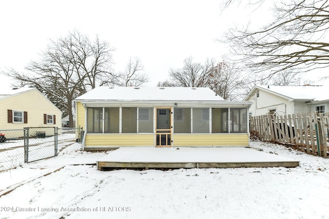 snow covered property featuring a wooden deck and a sunroom