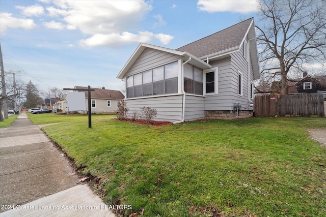 view of property exterior featuring a sunroom and a lawn