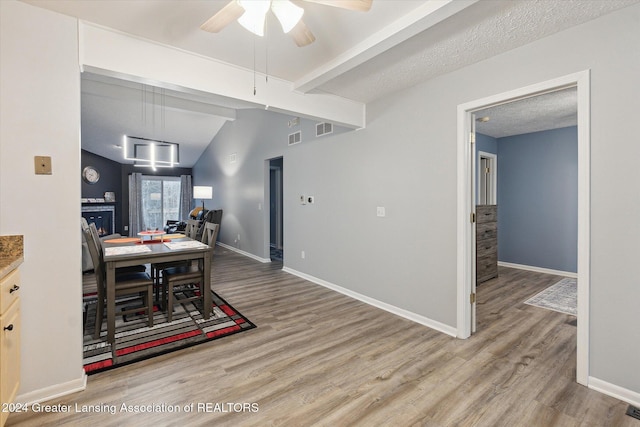 dining area featuring vaulted ceiling with beams, a textured ceiling, ceiling fan, and hardwood / wood-style floors