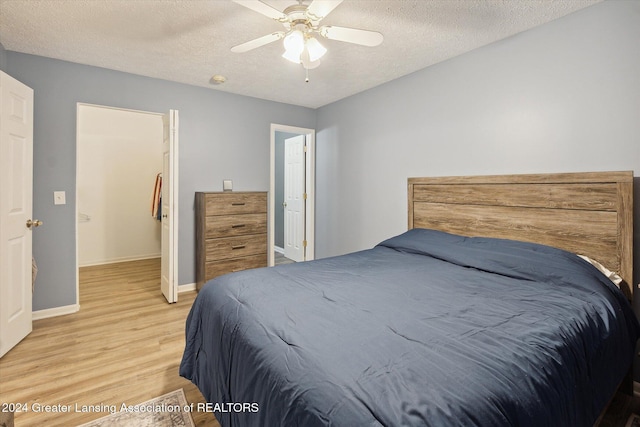 bedroom featuring ceiling fan, light hardwood / wood-style floors, and a textured ceiling