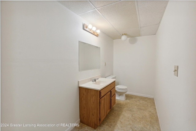 bathroom featuring vanity, toilet, and a drop ceiling