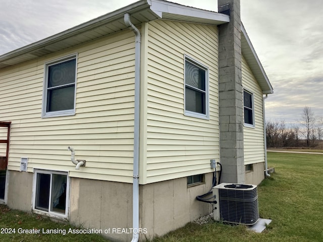 view of home's exterior with central air condition unit and a lawn