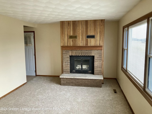 unfurnished living room featuring carpet flooring and a brick fireplace