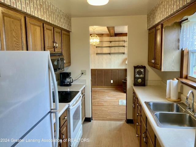 kitchen featuring white appliances, an inviting chandelier, sink, hanging light fixtures, and light hardwood / wood-style floors