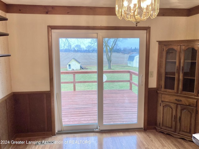 doorway to outside with light hardwood / wood-style flooring and a chandelier