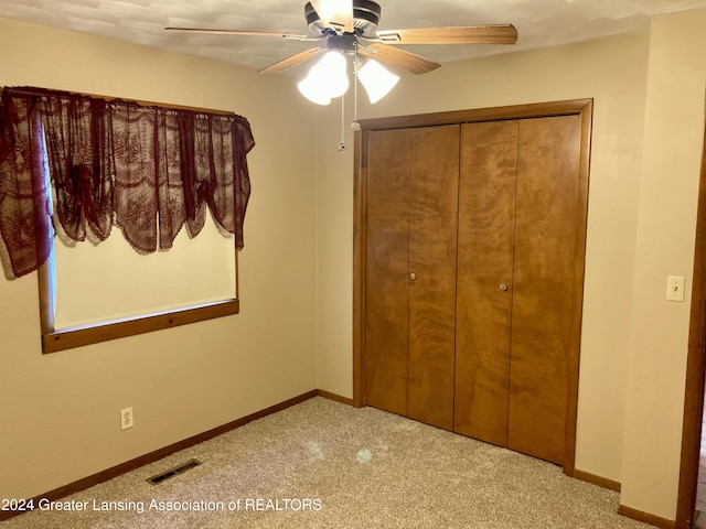 unfurnished bedroom with light carpet, a closet, and ceiling fan