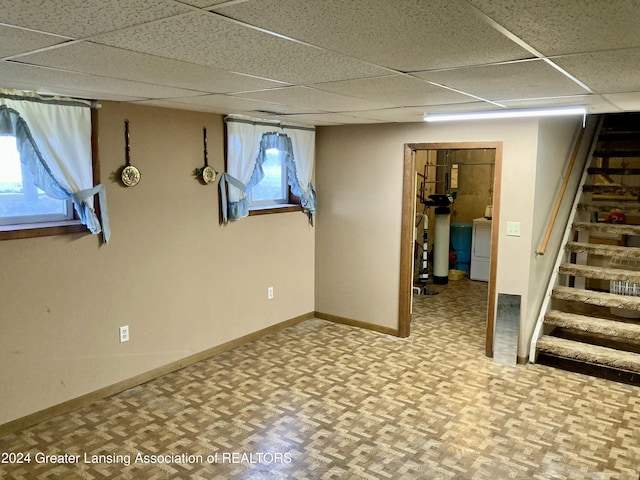 basement with a drop ceiling and washer / dryer