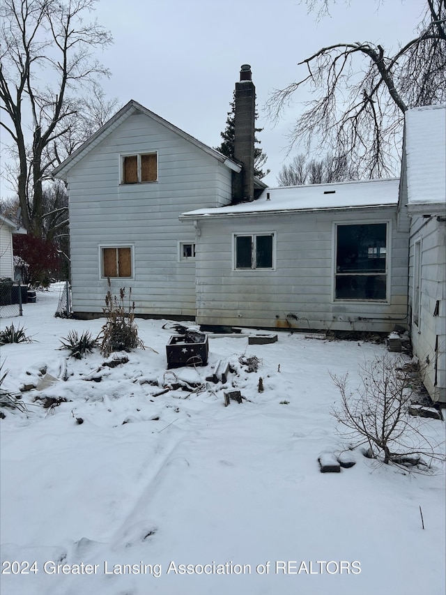 snow covered rear of property featuring a fire pit