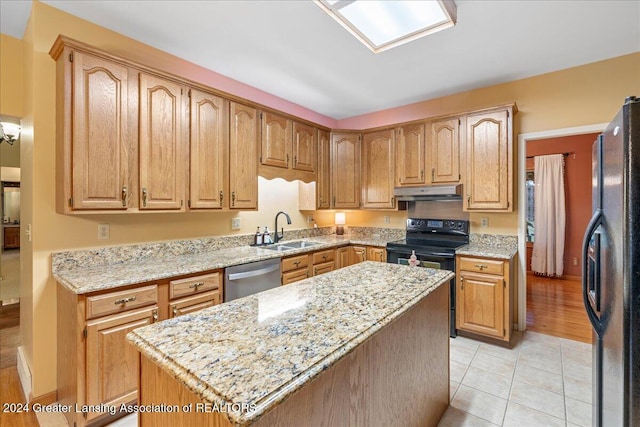 kitchen with light stone countertops, sink, black appliances, a center island, and light tile patterned flooring