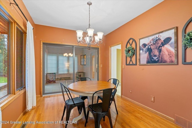 dining area with light hardwood / wood-style flooring and a chandelier