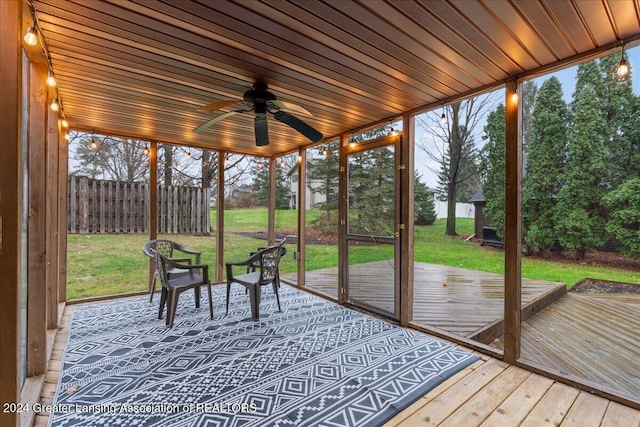 unfurnished sunroom featuring ceiling fan, plenty of natural light, and wooden ceiling