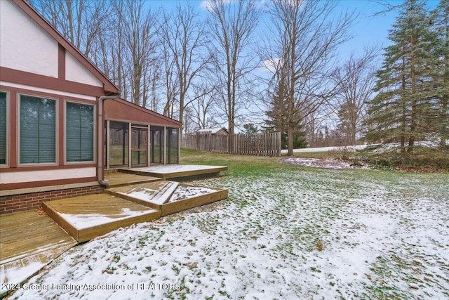 yard covered in snow featuring a sunroom and a deck