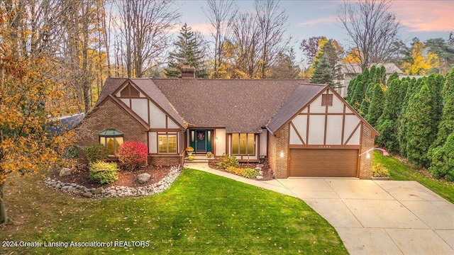 tudor-style house with a garage and a lawn