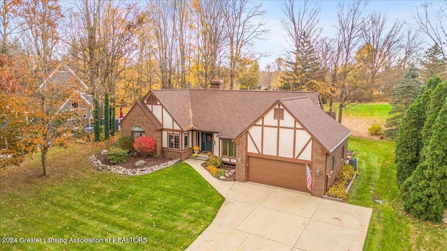 tudor house featuring a garage and a front lawn