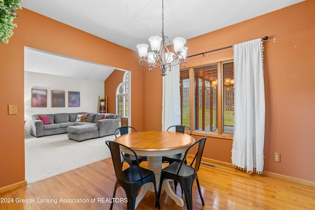 dining area with a chandelier, vaulted ceiling, light hardwood / wood-style flooring, and a healthy amount of sunlight