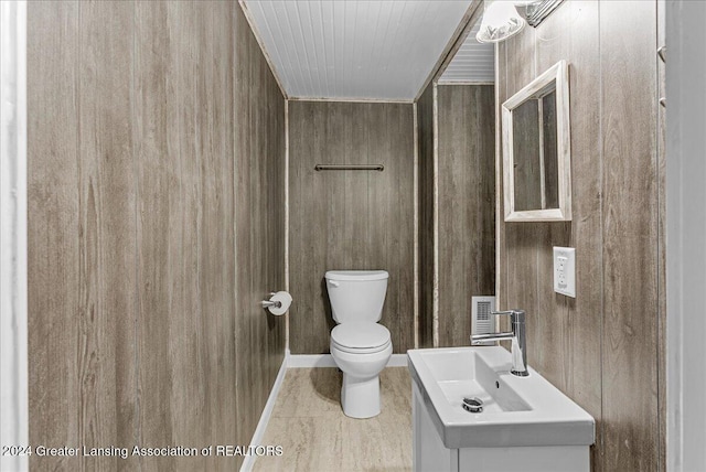 bathroom with vanity, toilet, and wooden walls