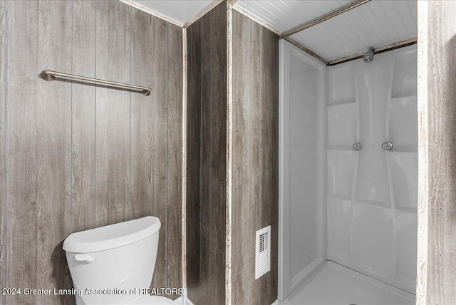 bathroom featuring wooden walls, a shower, and toilet