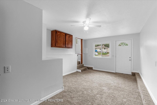 carpeted spare room featuring ceiling fan and a textured ceiling