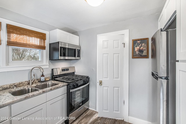 kitchen featuring sink, white cabinetry, appliances with stainless steel finishes, dark hardwood / wood-style flooring, and light stone countertops