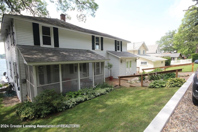 rear view of house with a sunroom, a deck, and a lawn