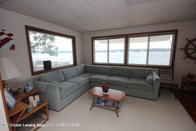 living room with carpet flooring, a drop ceiling, a water view, and plenty of natural light