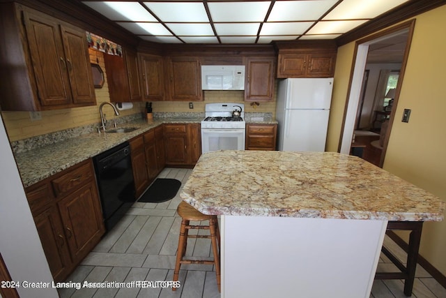 kitchen with white appliances, a center island, a breakfast bar area, and sink